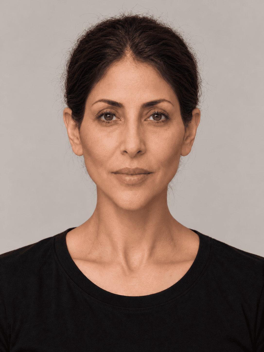 Woman, front view, with olive skin and straight dark brown hair pulled back in a low bun.
