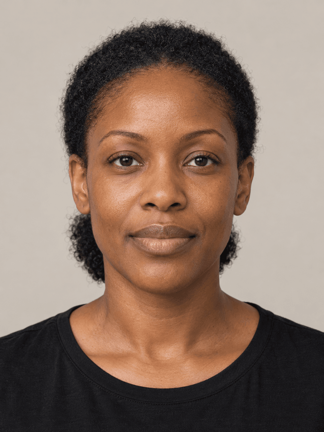 Woman, front view, with deep brown skin and natural tightly coily black 4c hair pulled back in a low puff behind the head.