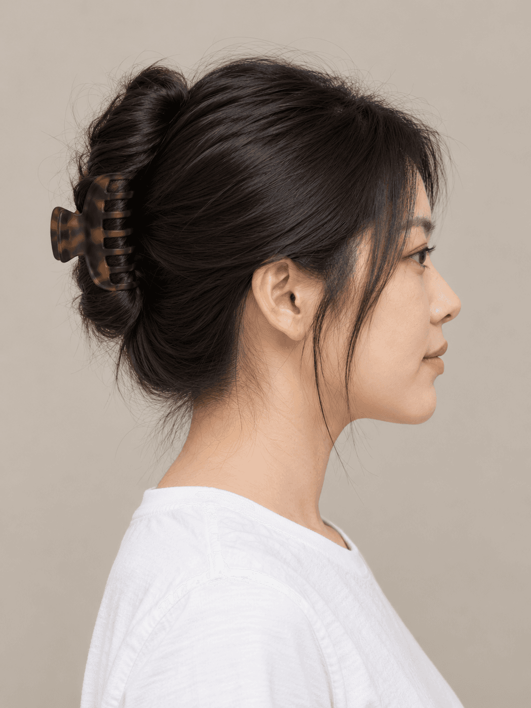 Claw-clip twist on a woman with light skin and straight black hair, side view