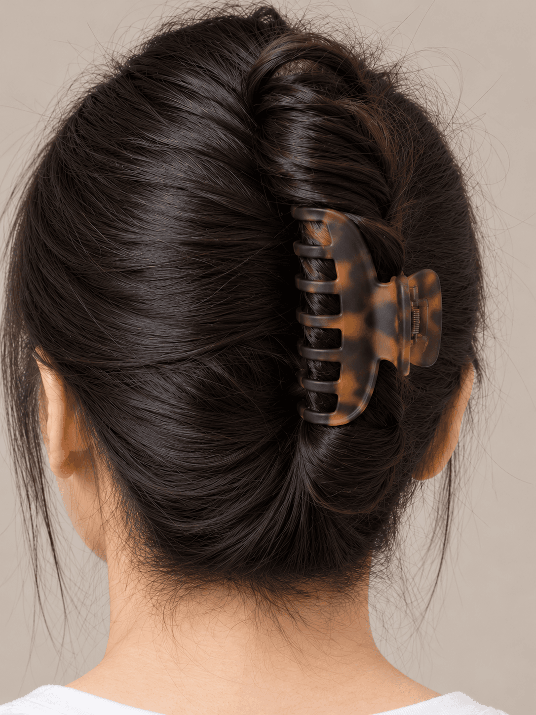 Claw-clip twist on a woman with light skin and straight black hair, close view of the twist and the clip from the back