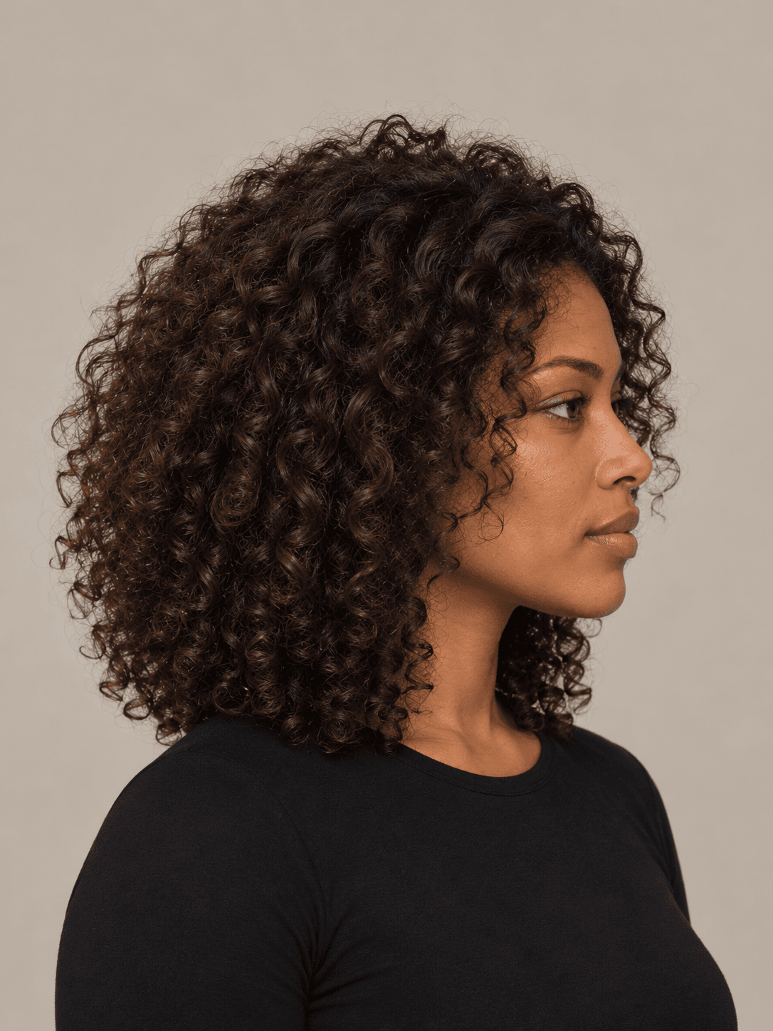Curly layers hairstyle on a woman with dark brown curly hair, side view