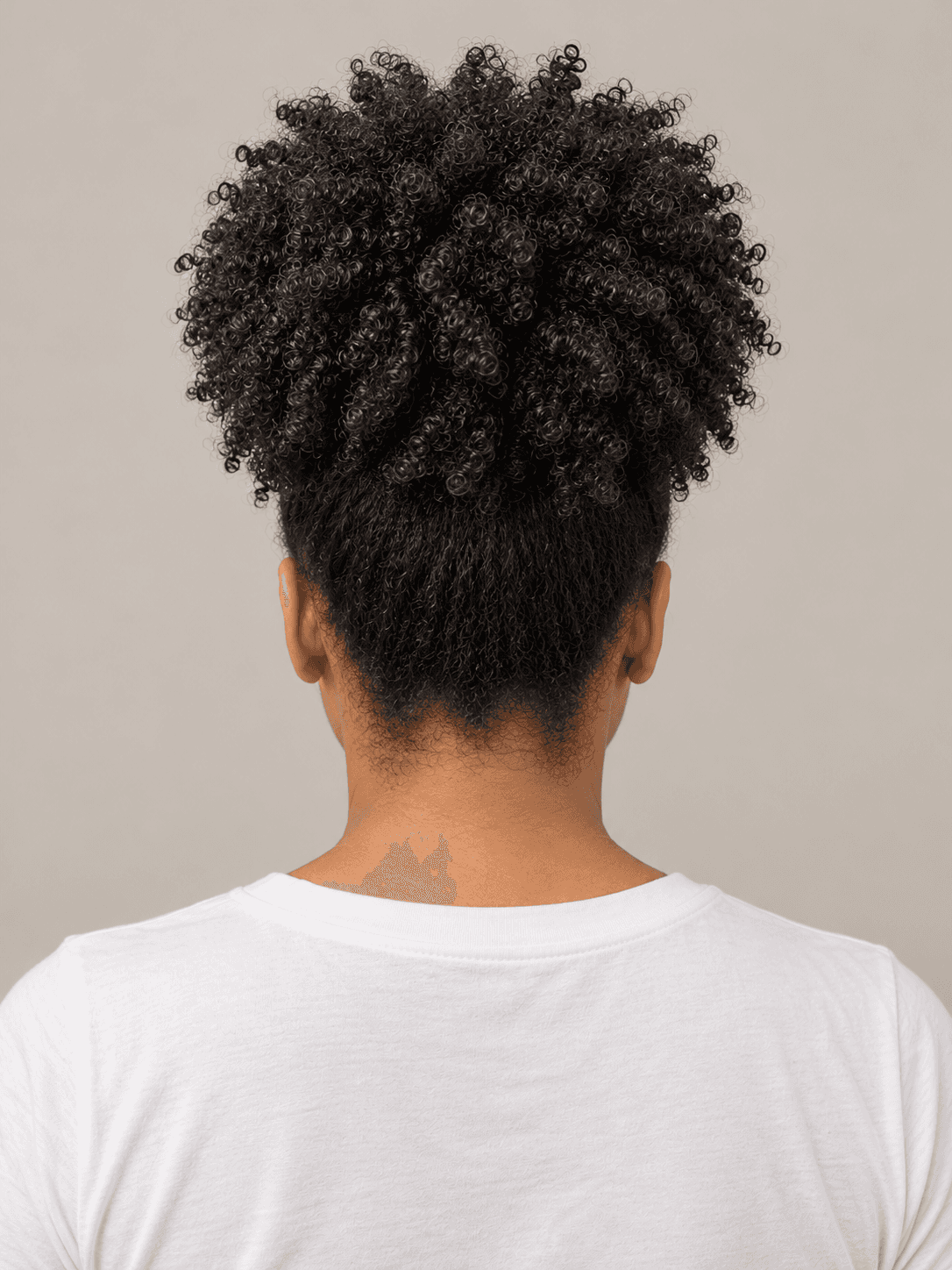 High puff on a woman with medium brown skin and coily hair, back view