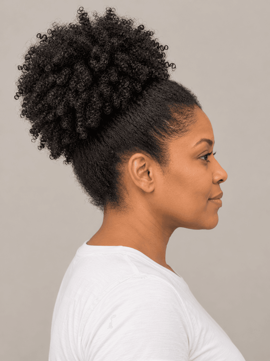 High puff on a woman with medium brown skin and coily hair, side view
