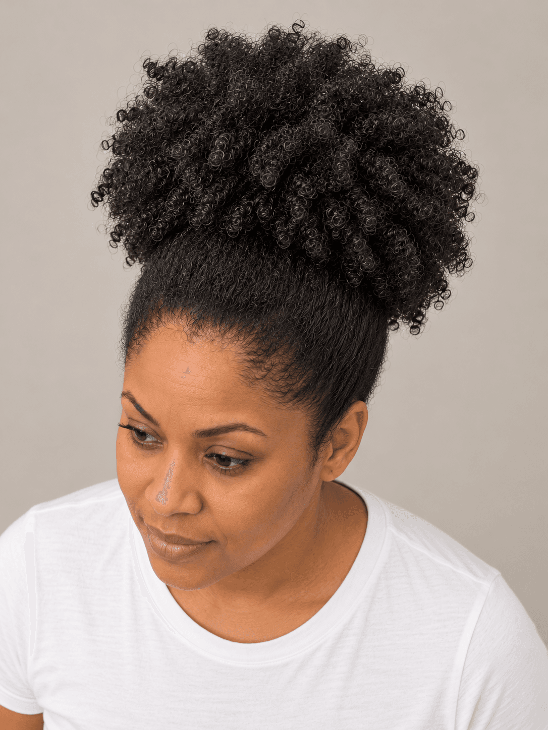 High puff on a woman with medium brown skin and coily hair, seen from above to show the round shape of the puff