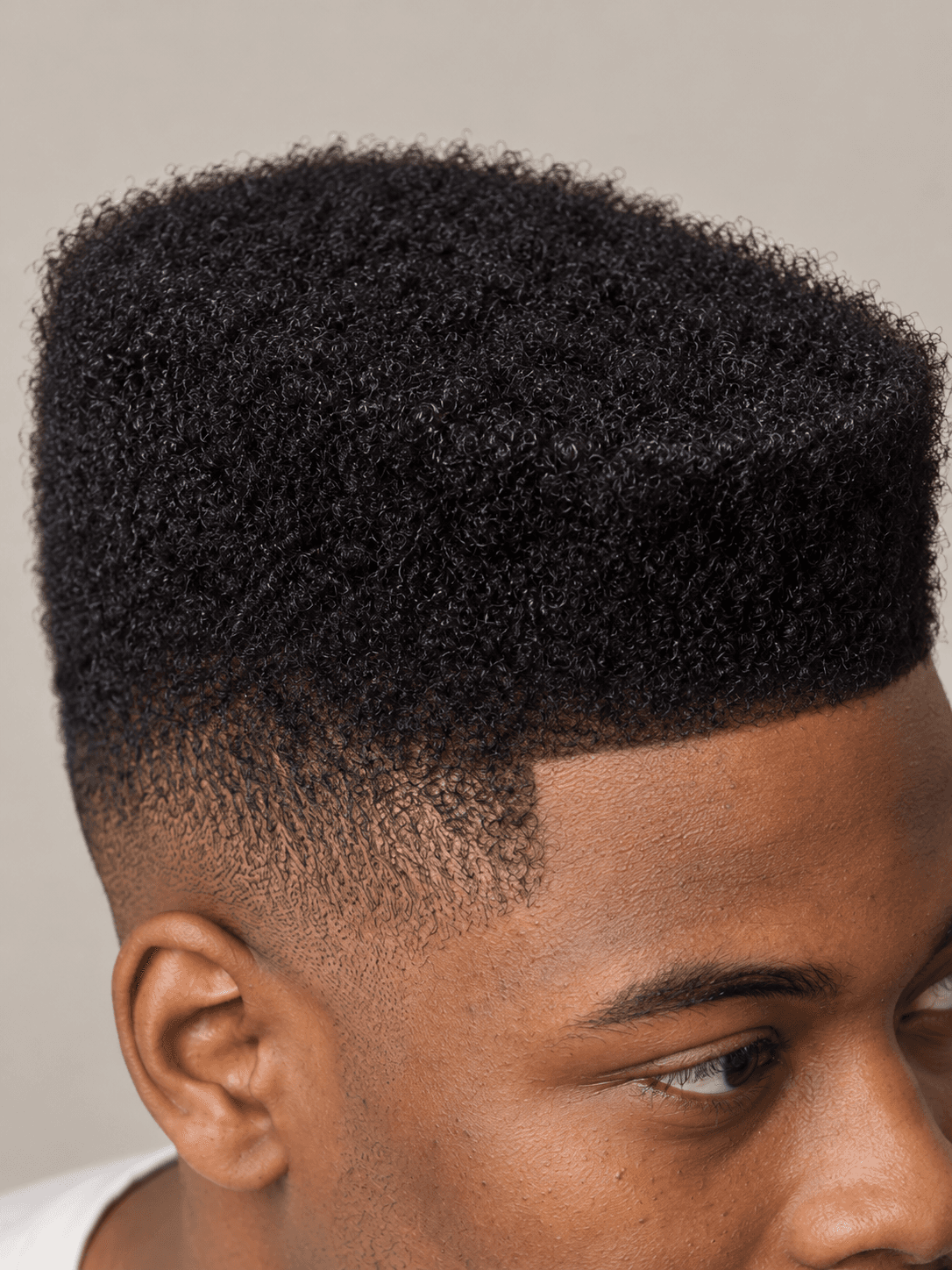 High-Top Fade on a man with coily black hair, close view of the flat top edge and the fade from the side