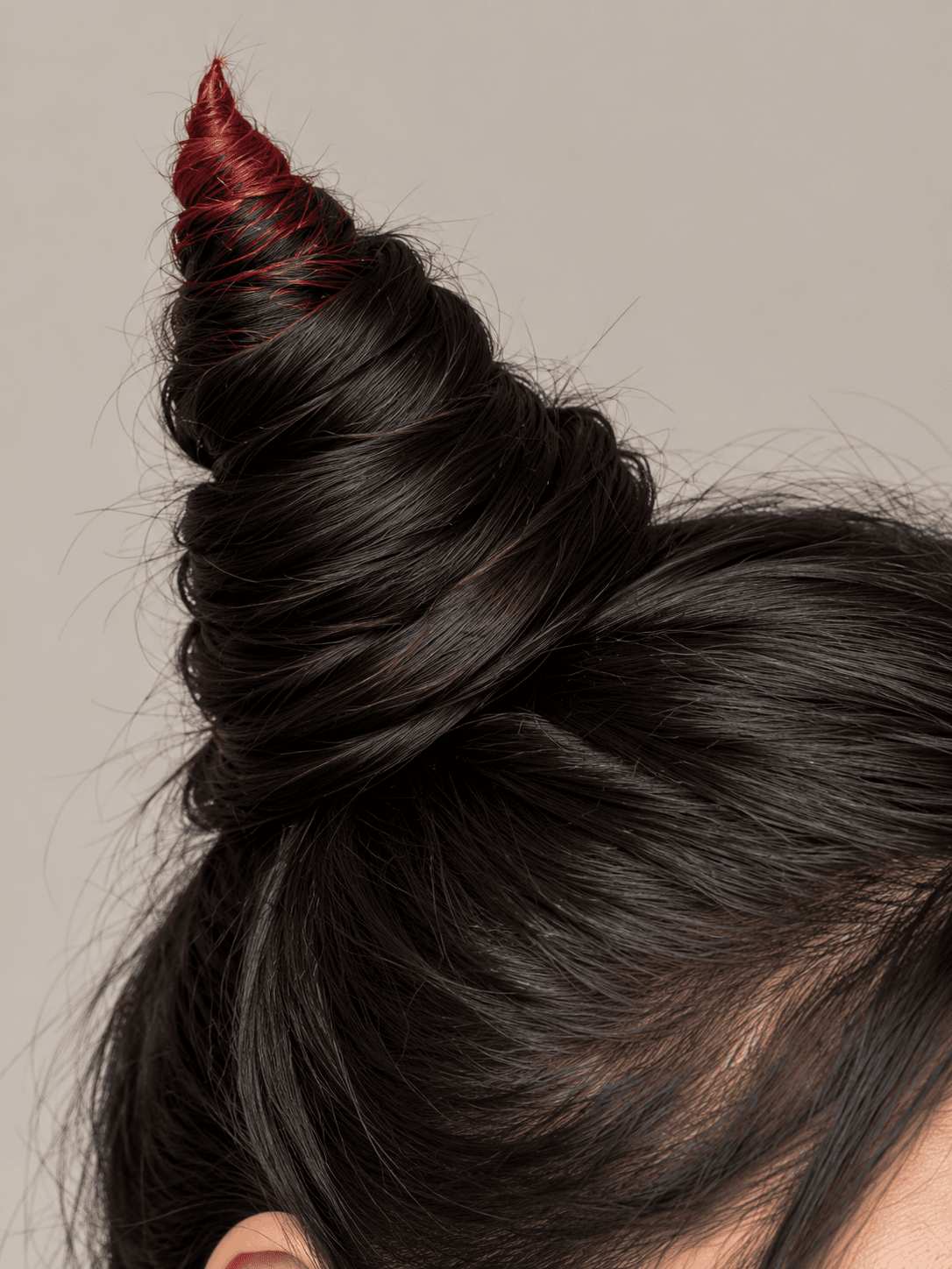 Horn Buns on a woman with light tan skin and black hair, close side view of one twisted bun, with red colour on the tip only