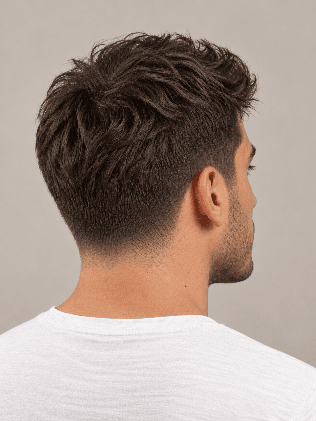 Low Taper Fade on a man with wavy dark brown hair, three-quarter view