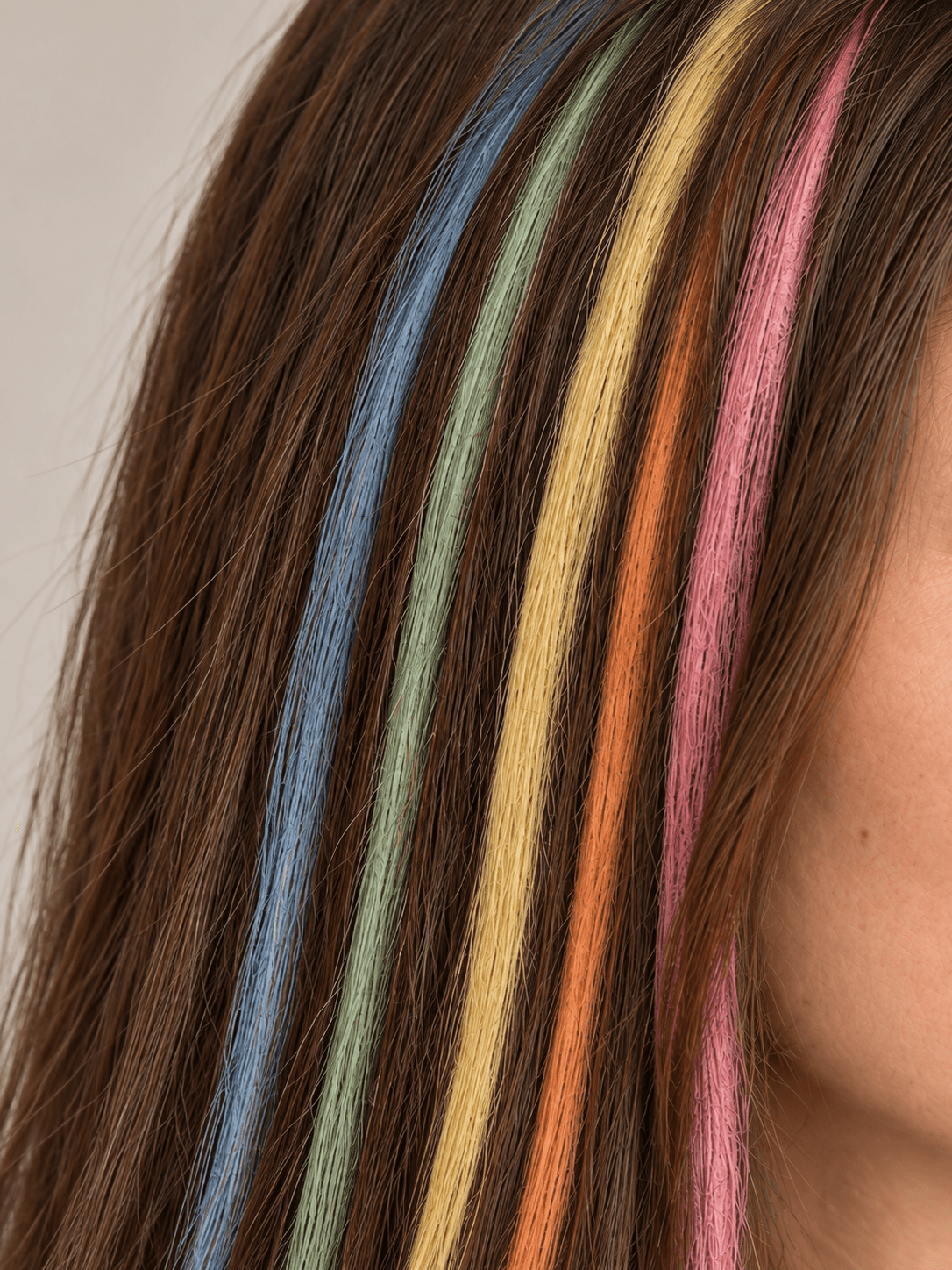 Rainbow Chalk Streaks on a woman with light skin and brown hair, close view of the chalked strands, each in a separate colour