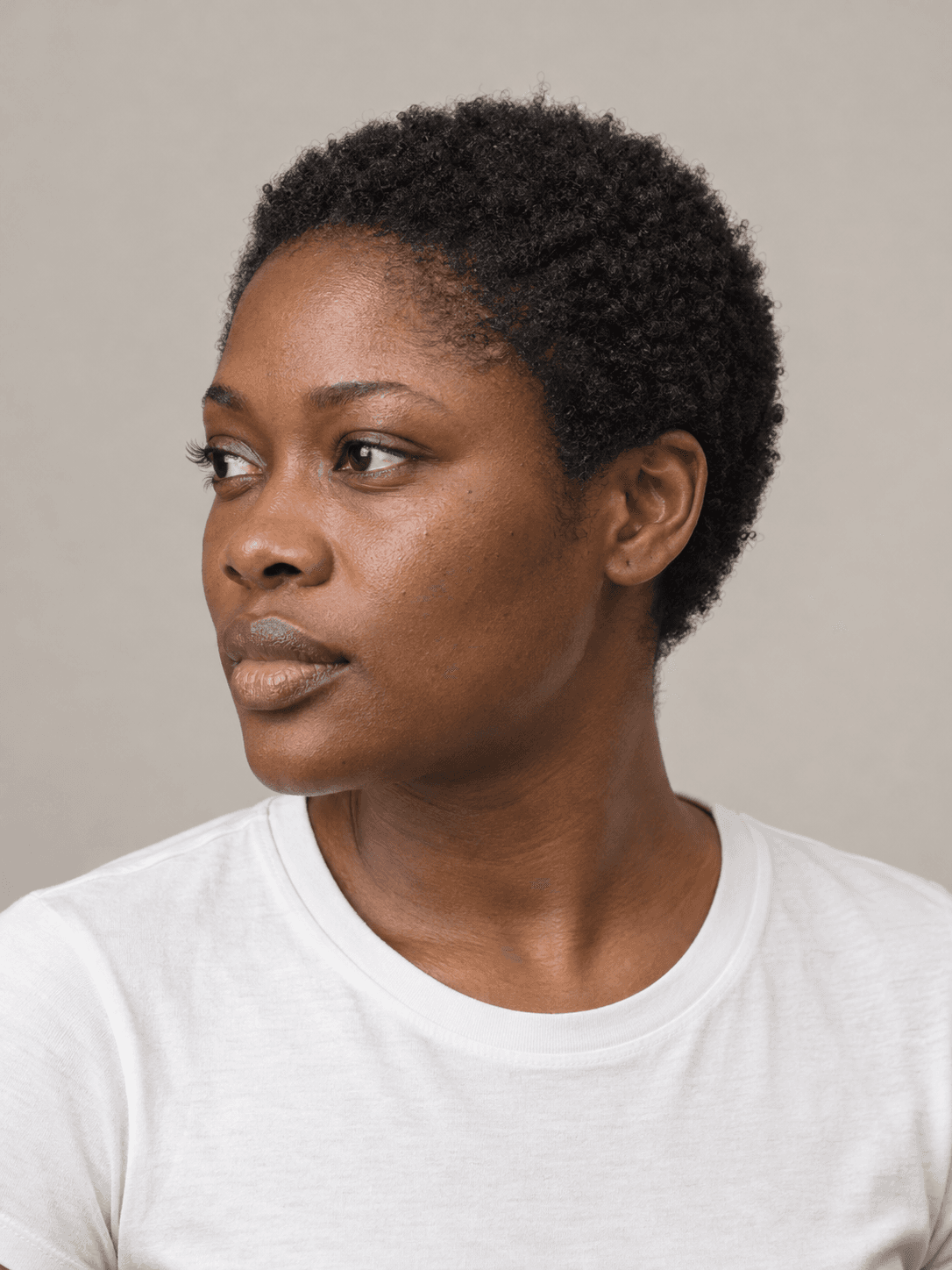 Short natural afro on a woman with dark brown skin and tightly coiled black hair, three-quarter view