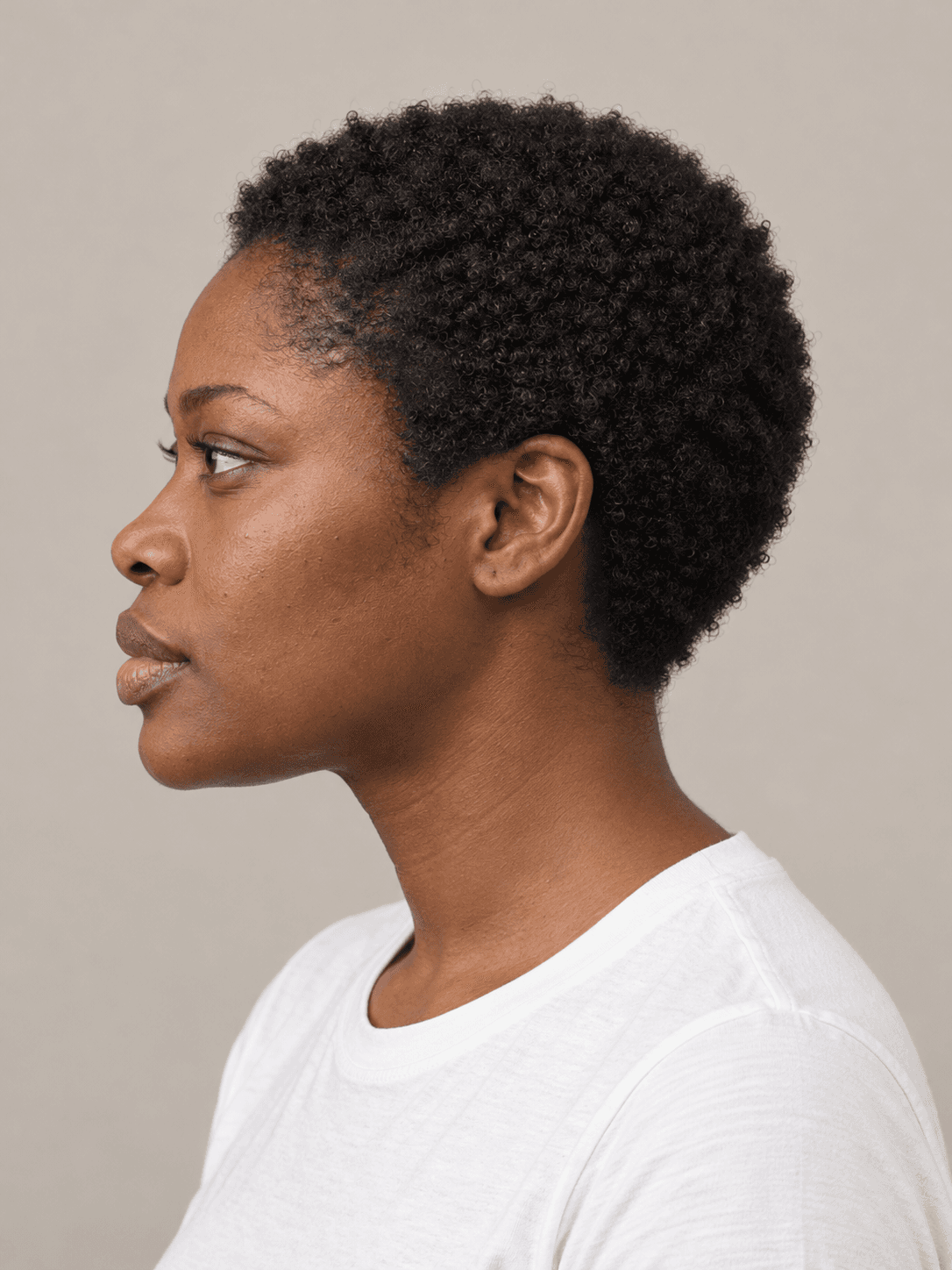 Short natural afro on a woman with dark brown skin and tightly coiled black hair, side view