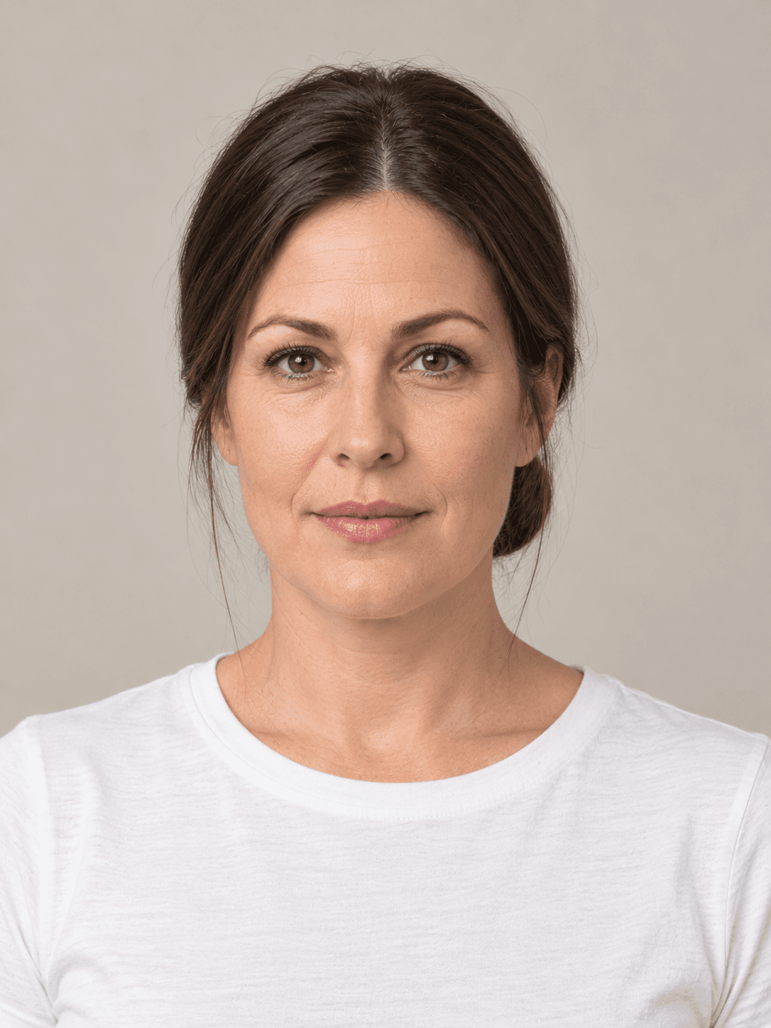 Sleek low bun on a woman with light skin and straight dark brown hair, front view