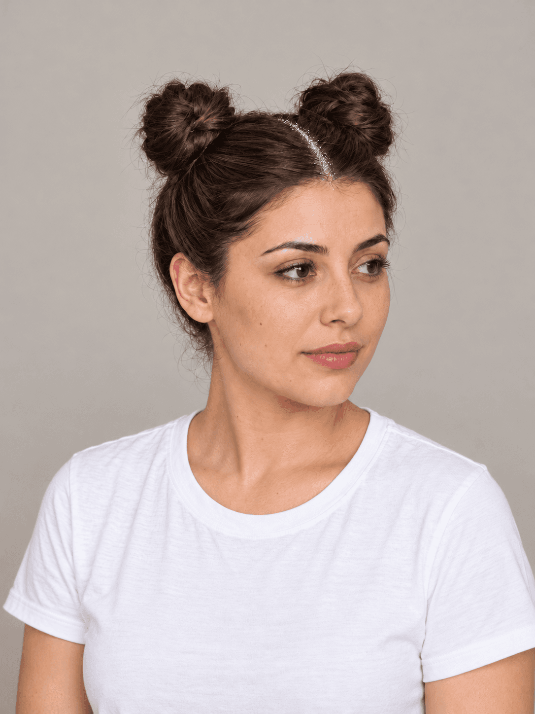 Space Buns with Glitter Roots on a woman with light olive skin and dark brown hair, three-quarter view