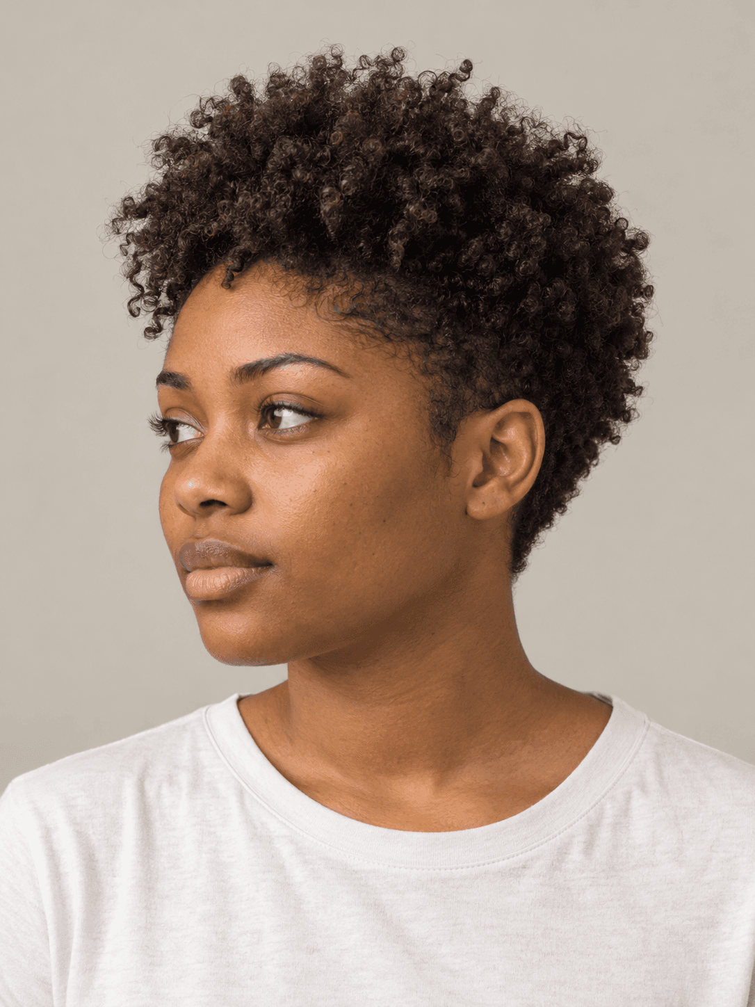 Tapered curly fro on a woman with warm brown skin and dark brown curls, three-quarter view