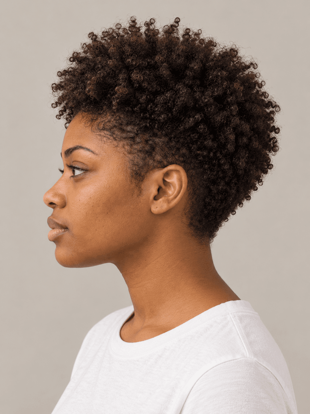Tapered curly fro on a woman with warm brown skin and dark brown curls, side view