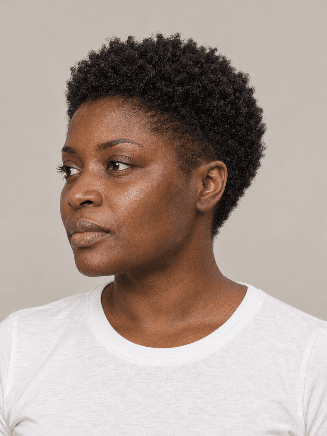 Tapered natural cut on a woman with deep brown skin and coily black hair, three-quarter view