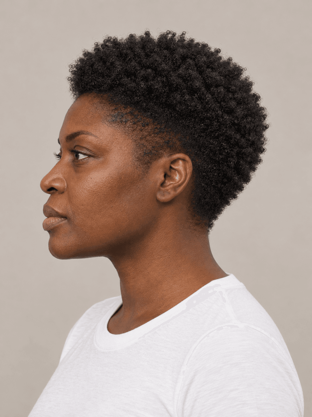 Tapered natural cut on a woman with deep brown skin and coily black hair, side view