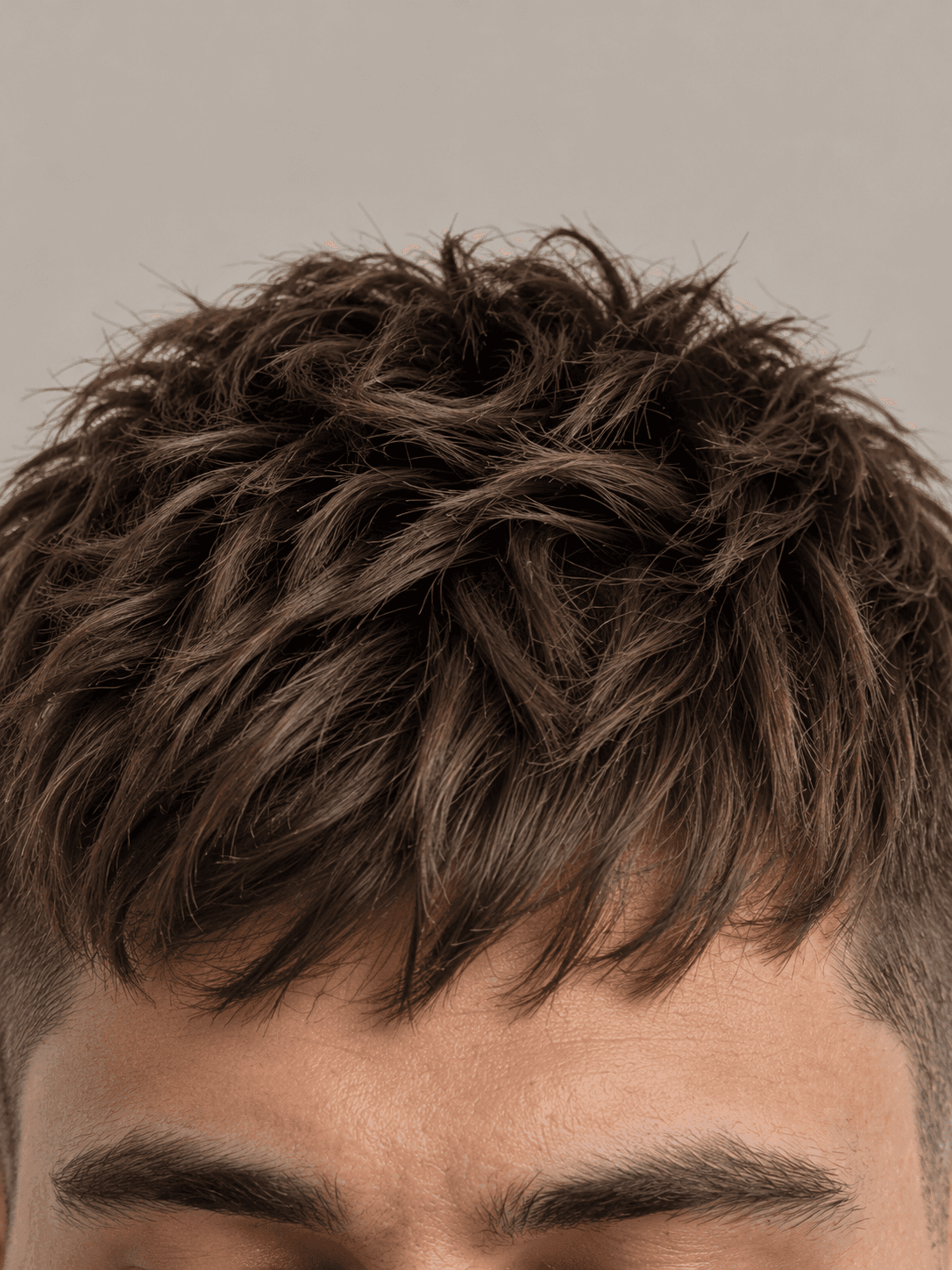 Textured crop hairstyle with a short fringe on a man with dark brown hair, close-up of the textured fringe