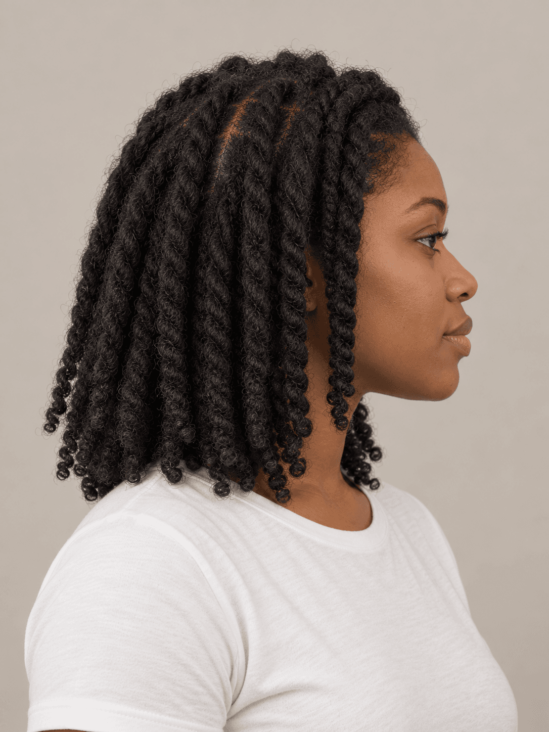 Two-strand twists on a woman with dark brown skin and coily hair, side view