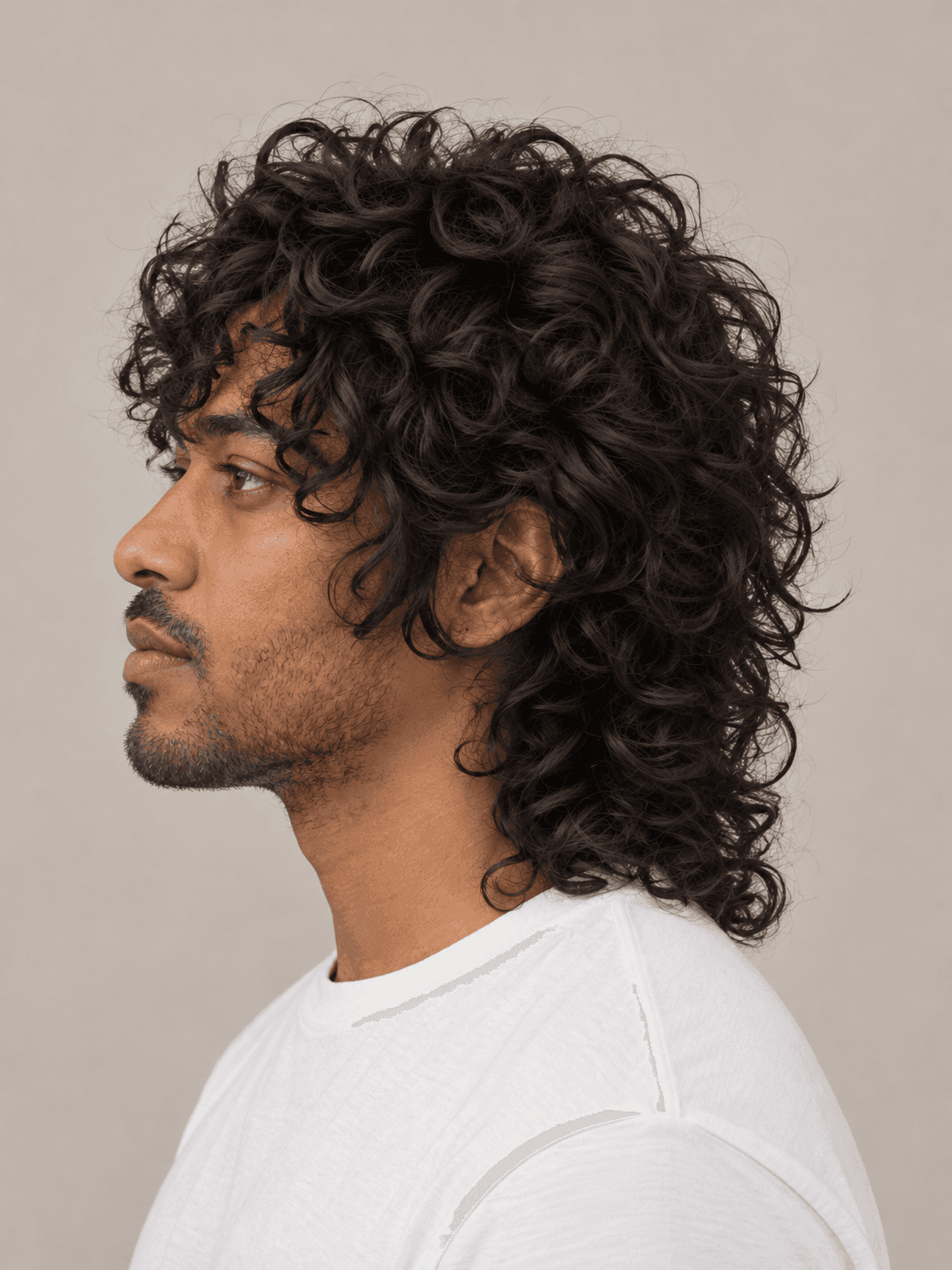 Wolf cut hairstyle on a man with dark curly hair, side view
