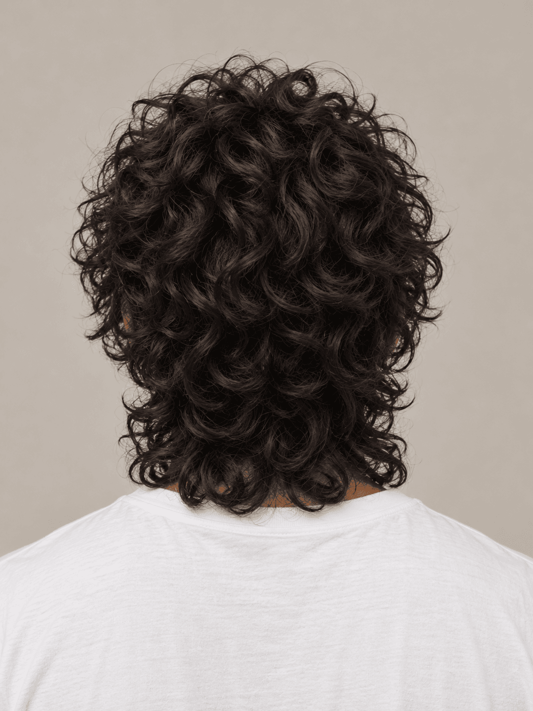 Wolf cut hairstyle on a man with dark curly hair, back view