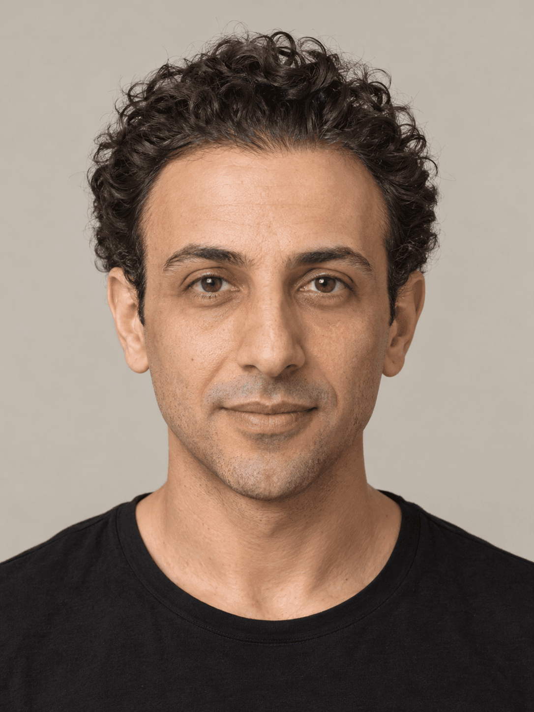 Man, front view, with olive skin and curly dark brown hair brushed straight back.