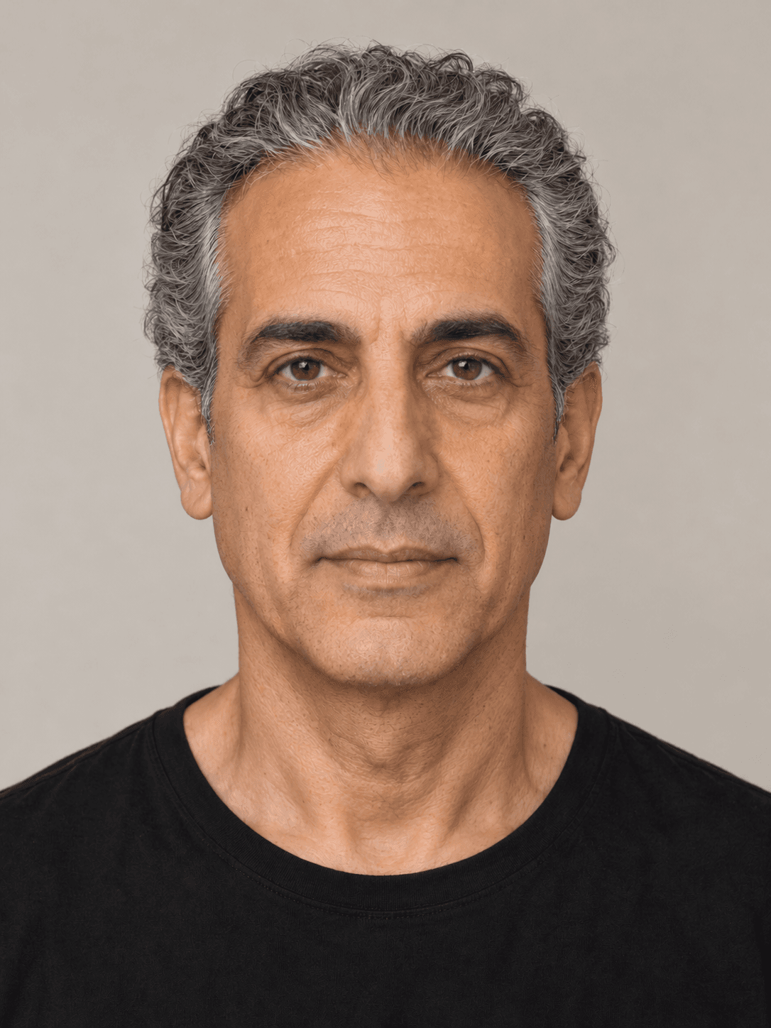 Man, front view, with olive skin and wavy grey hair brushed straight back.