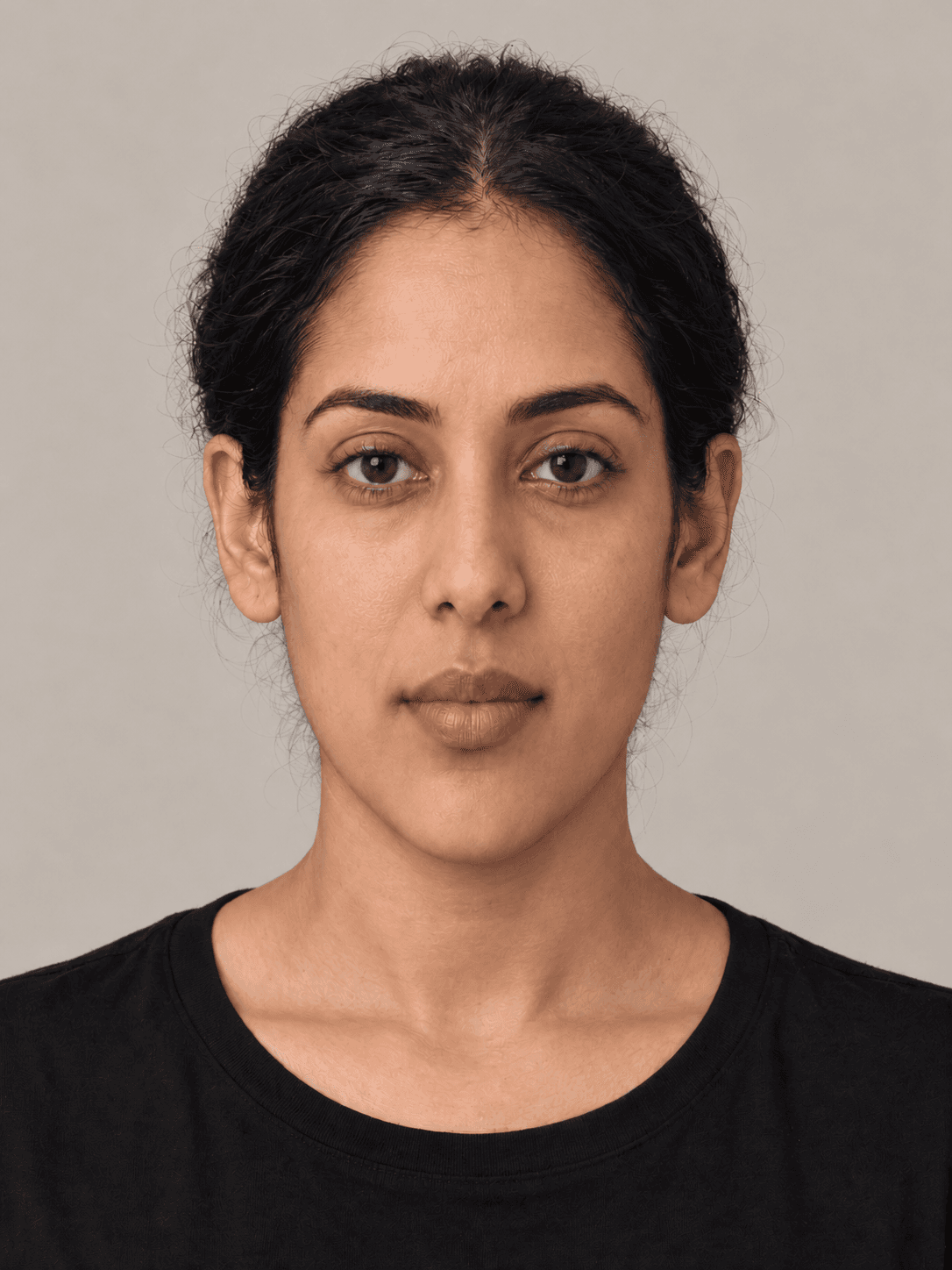 Woman, front view, with medium brown skin and wavy black hair pulled back in a low bun.