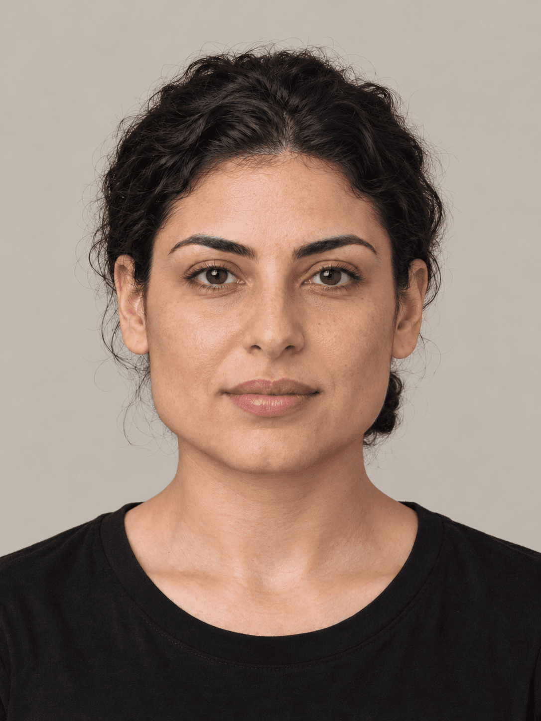 Woman, front view, with light olive skin and wavy black hair pulled back in a low bun.