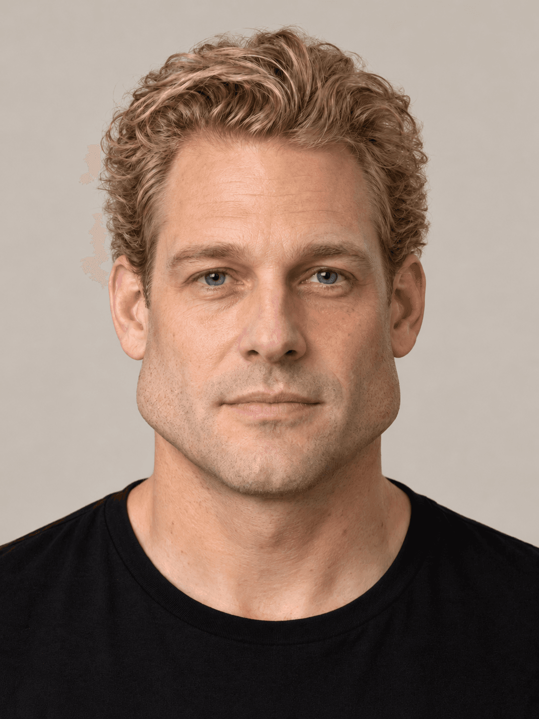 Man, front view, with fair skin and wavy blond hair brushed straight back.