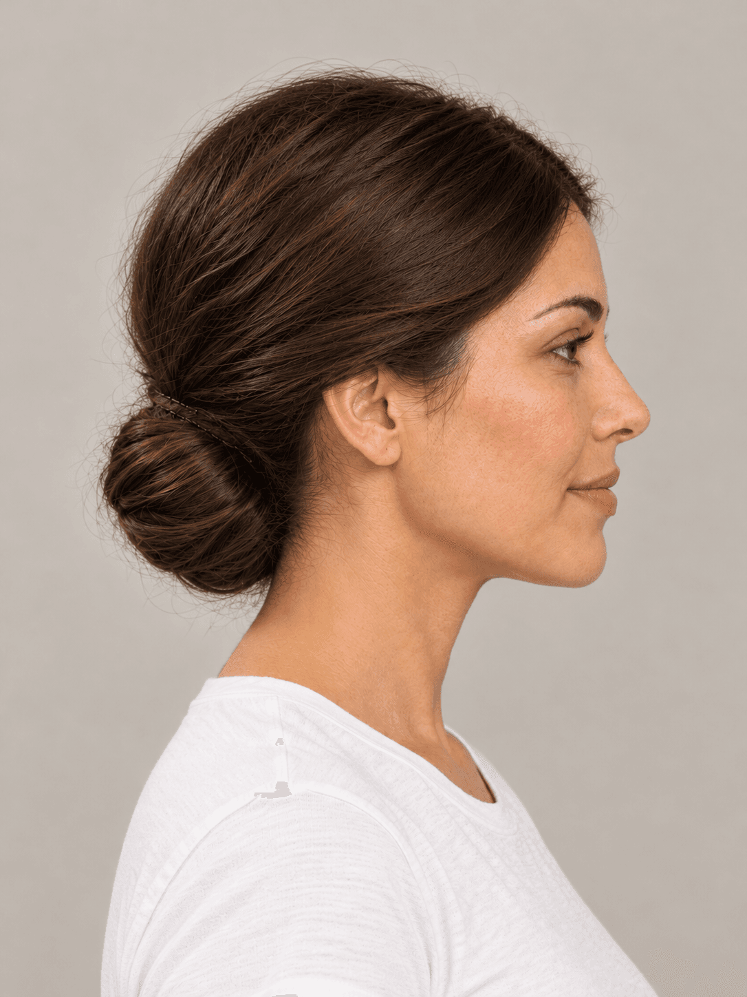 Low Chignon on a woman with light olive skin and dark brown hair, side view